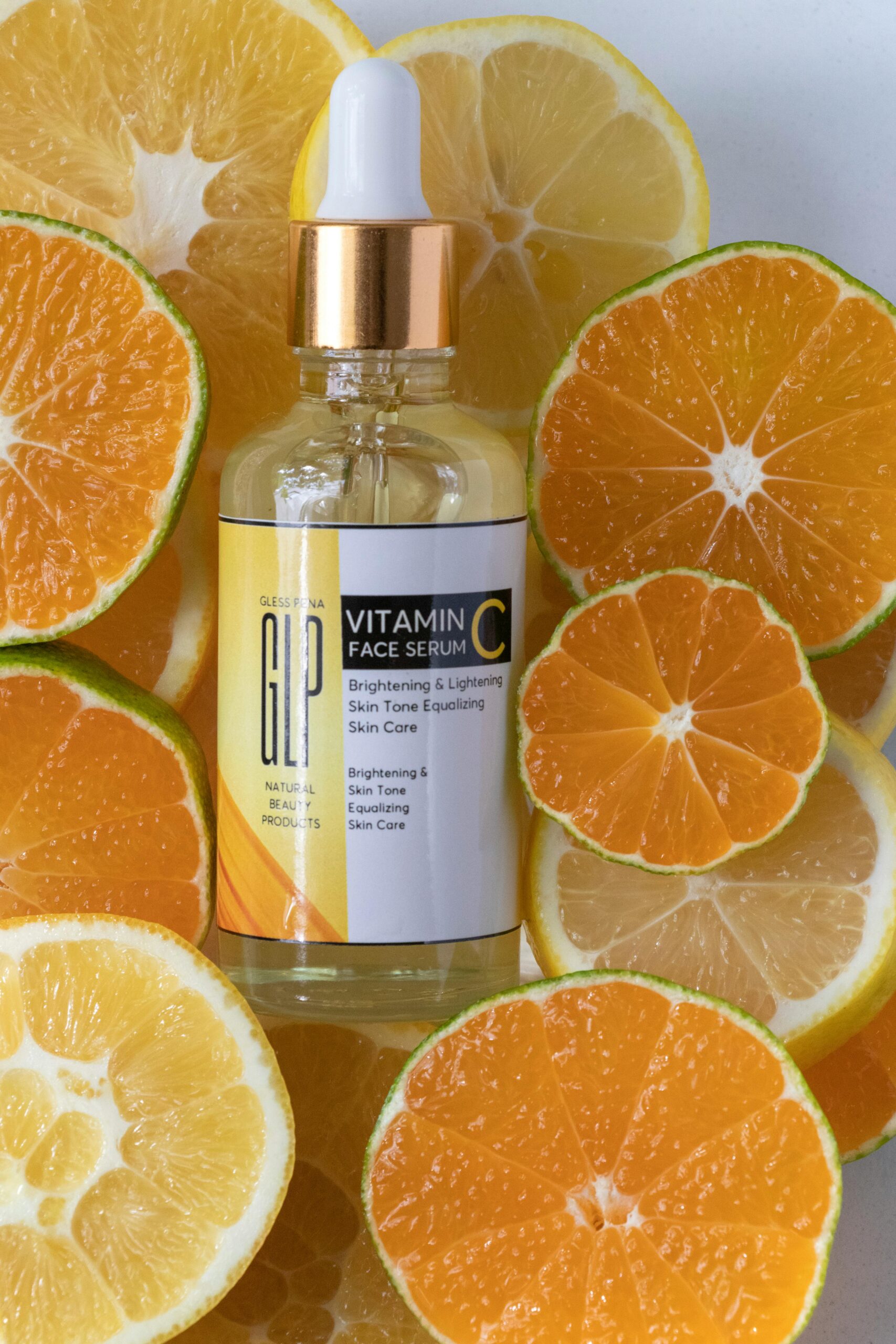 Brightening vitamin C serum surrounded by fresh sliced citrus fruits in a studio setting.